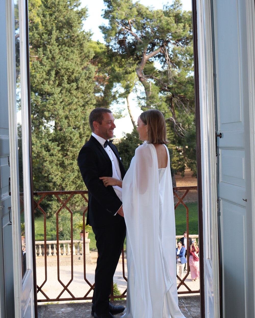 Bride and groom laughing together on a balcony