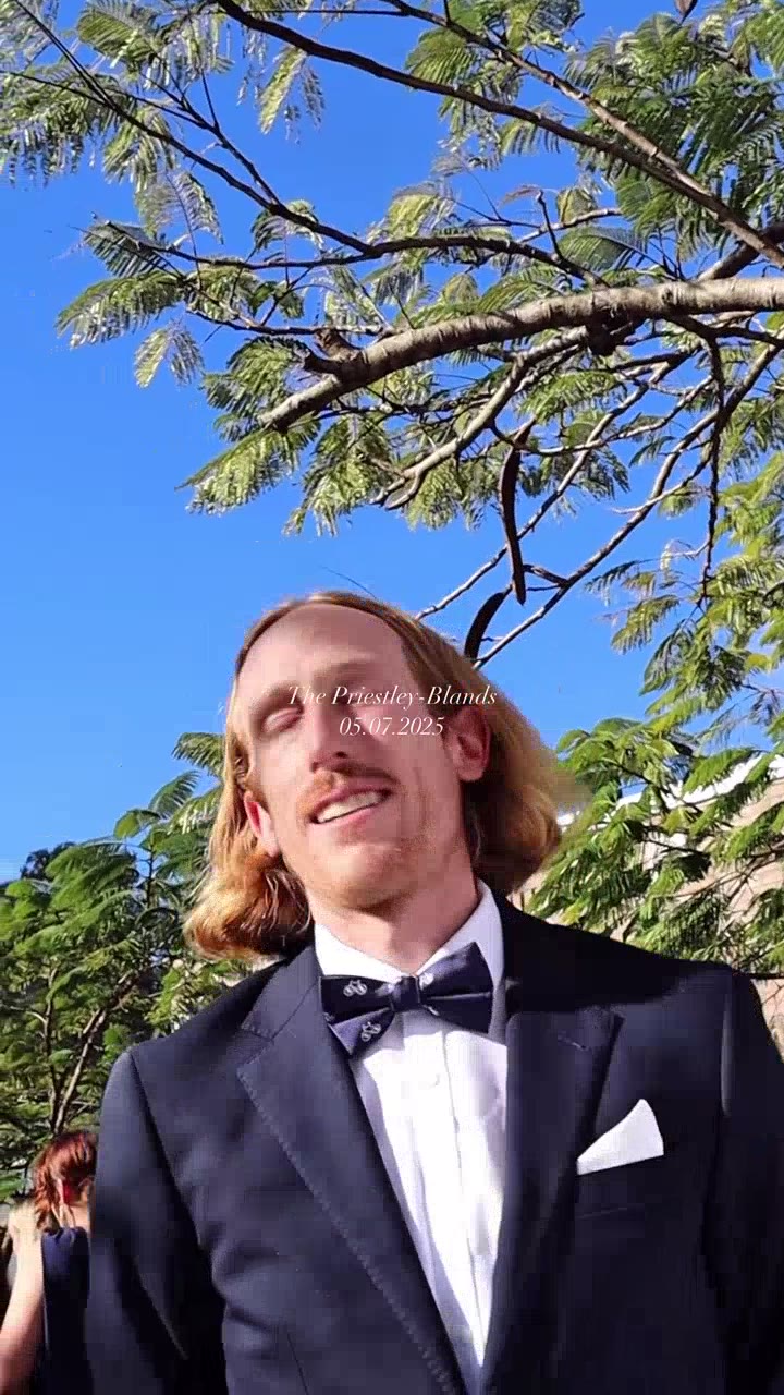 Groom laughing outdoors under trees on the wedding day