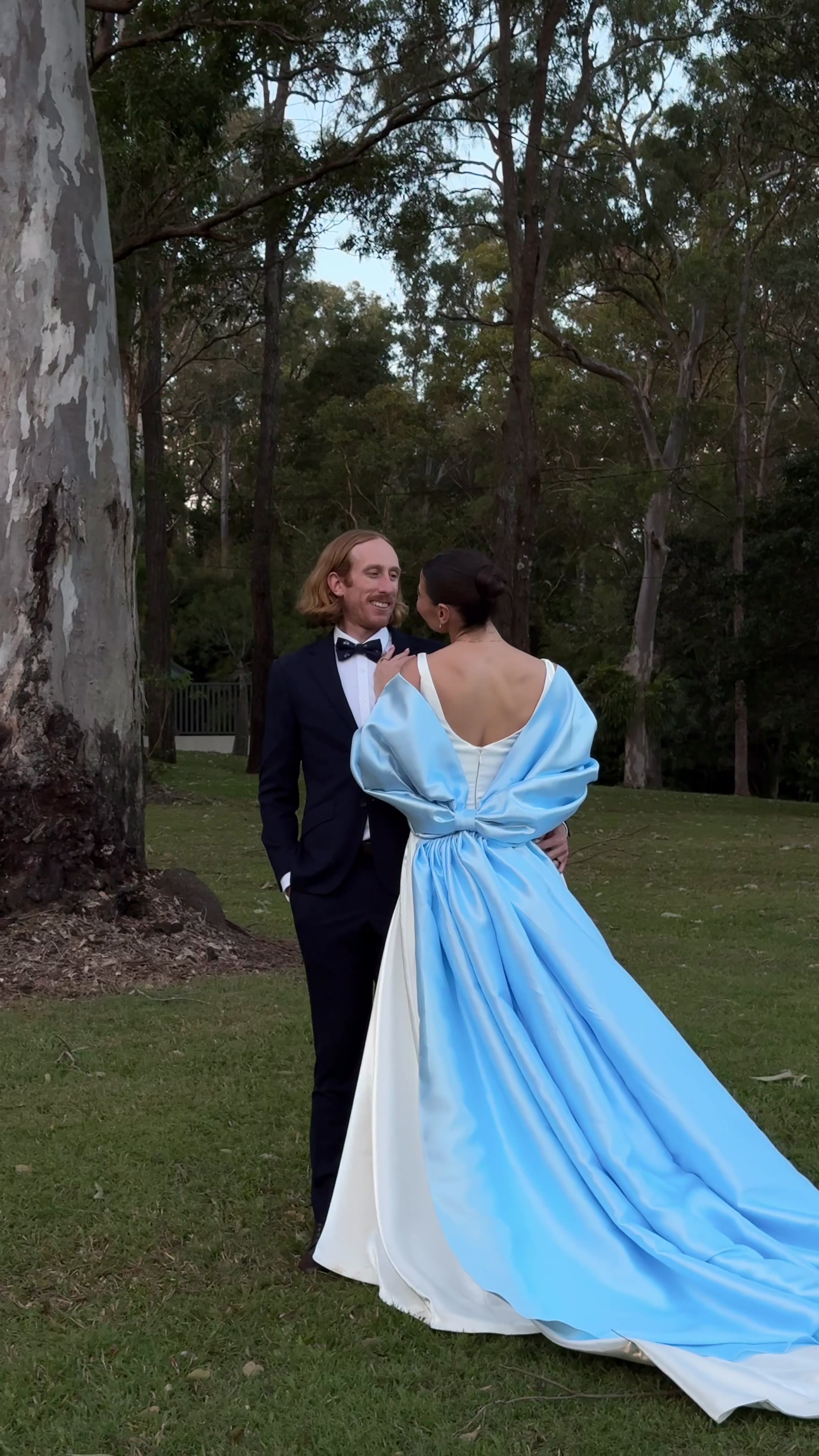Bride and groom embracing outdoors in a blue satin wrap dress