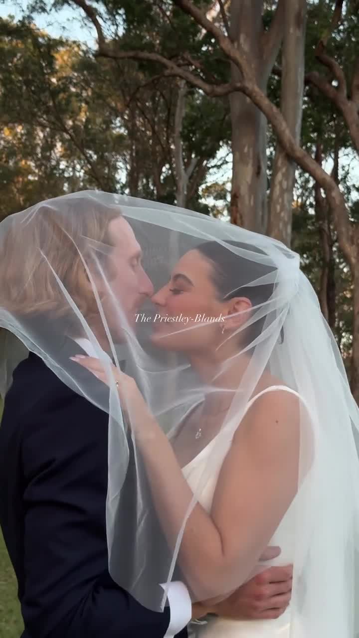 Bride and groom kissing under her veil at sunset